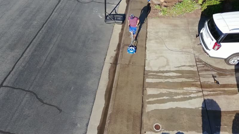 Surface cleaner pass on a concrete driveway showing clean and dirty halves