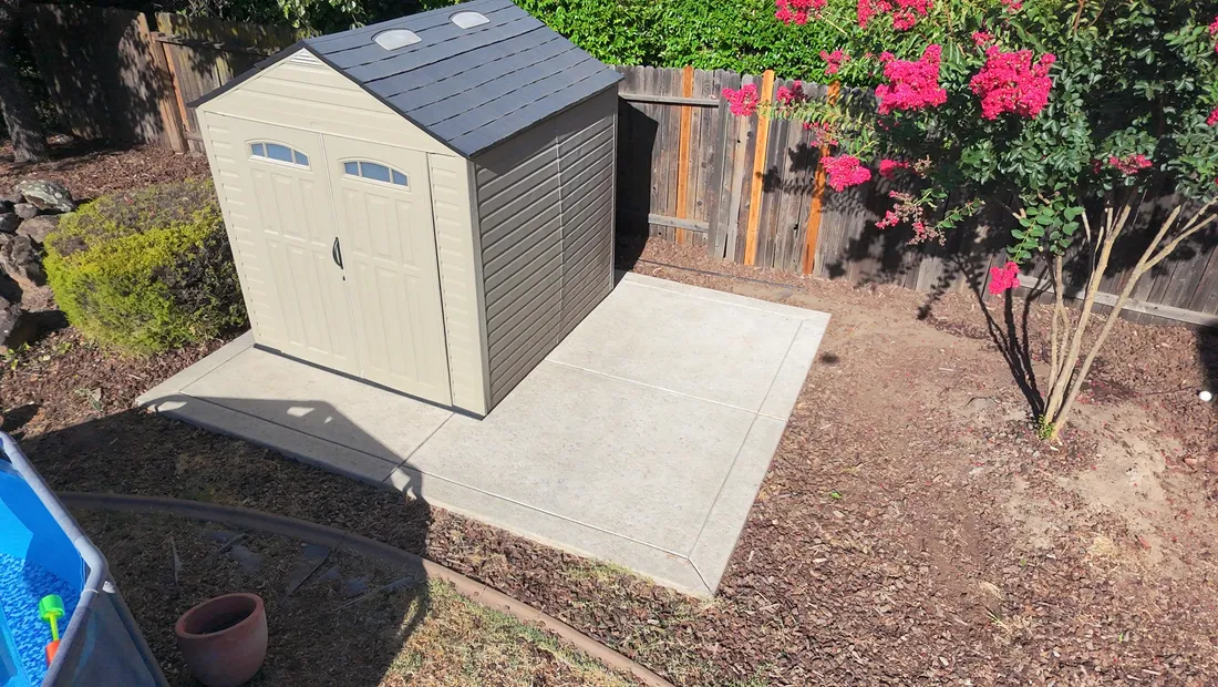 Clean concrete pad around a backyard shed after pressure washing in the Rocklin area
