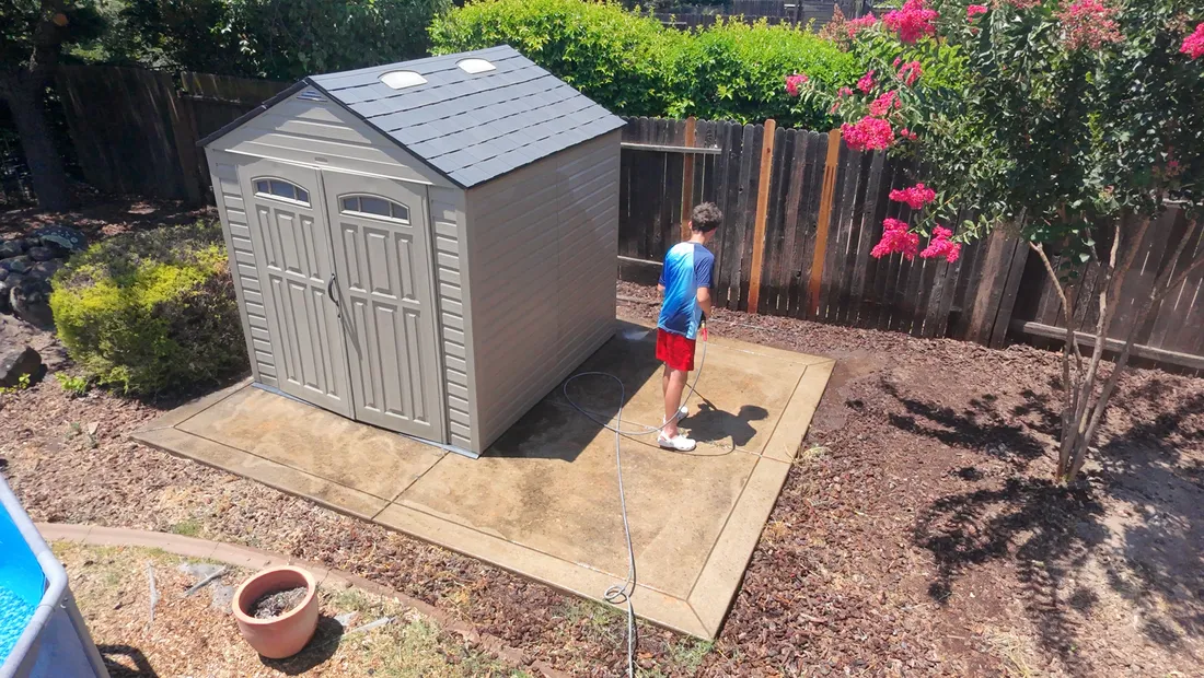 Concrete pad around a backyard shed being pressure washed in the Rocklin area, before cleaning